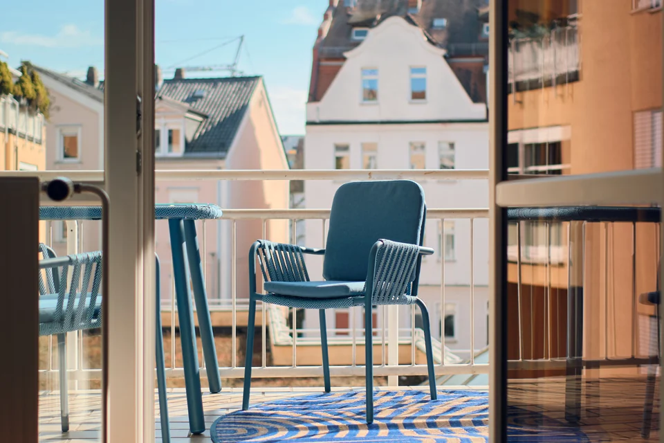 Sitzmöbel am Balkongeländer mit Blick auf die gegenüberliegenden Häuser. – Apartment Mittendrin.